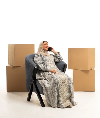 Khaleeji Woman with Moving Boxes Talking on Phone