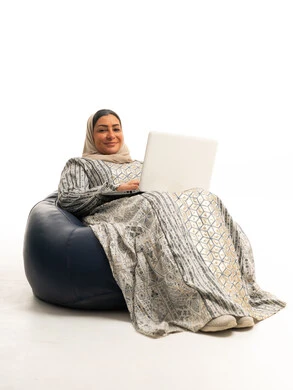 امرأة عربية مع لابتوب على مقعد محشو خلفية بيضاء
