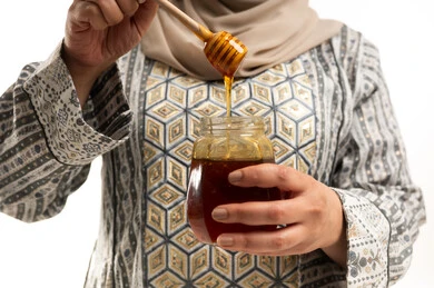 Arab Woman Holding Organic Honey Jar with Wooden Dipper