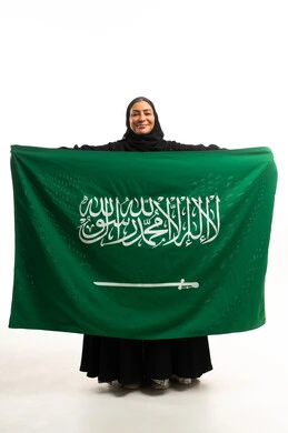 امرأة سعودية تحمل العلم السعودي بخلفية بيضاء