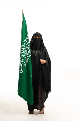 امرأة سعودية بالعباءة والنقاب تحمل علم المملكة