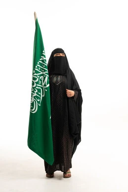 امرأة سعودية تحمل العلم الوطني بالعباءة والنقاب
