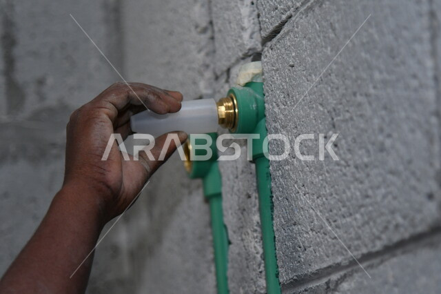 A close-up of the hand of a construction worker, Saudi professions and jobs, construction and construction development work in the Kingdom of Saudi Arabia, repairs and construction, maintenance and construction concept, water pipe network inside the build