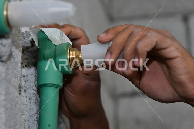 A close-up of the hand of a construction worker, Saudi professions and jobs, construction and construction development work in the Kingdom of Saudi Arabia, repairs and construction, maintenance and construction concept, water pipe network inside the build