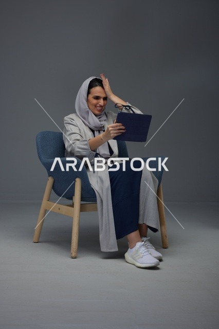 امرأة سعودية تستخدم جهاز لوحي بتعبيرات محبطة