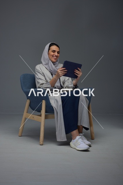 امرأة سعودية تستخدم جهازاً لوحياً في كرسي استوديو