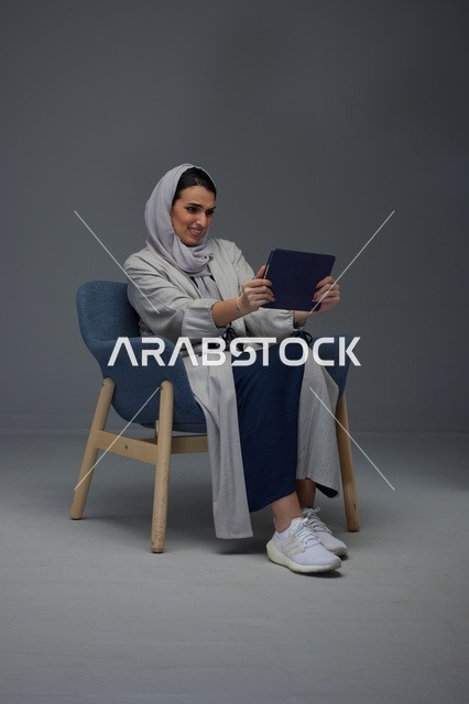 امرأة سعودية تستخدم جهاز لوحي على كرسي استوديو