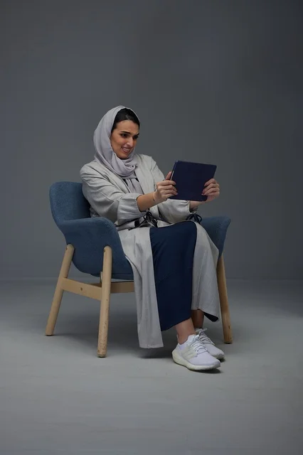 امرأة سعودية تستخدم جهاز لوحي على كرسي استوديو