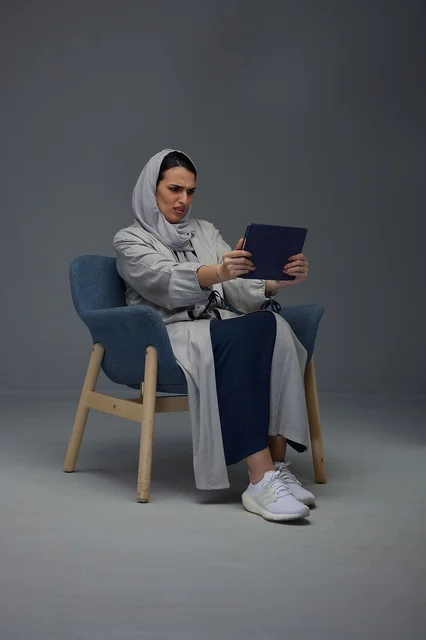امرأة سعودية تستخدم جهازاً لوحياً بتعبير وجه مرتبك