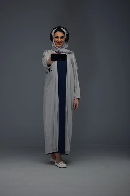 Saudi Woman with Headphones Holding Smartphone in Studio