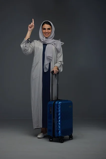 Saudi Woman Traveler Pointing Up with Blue Suitcase