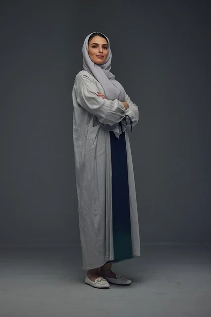 Saudi Woman in Grey Abaya Portrait Against Dark Background Saudi Woman in Grey Abaya Portrait Against Dark Background