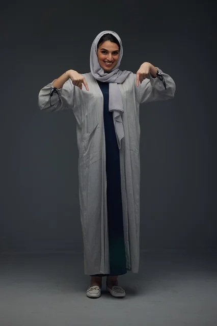 Saudi Woman in Grey Abaya Pointing Down Studio Portrait Saudi Woman in Grey Abaya Pointing Down Studio Portrait