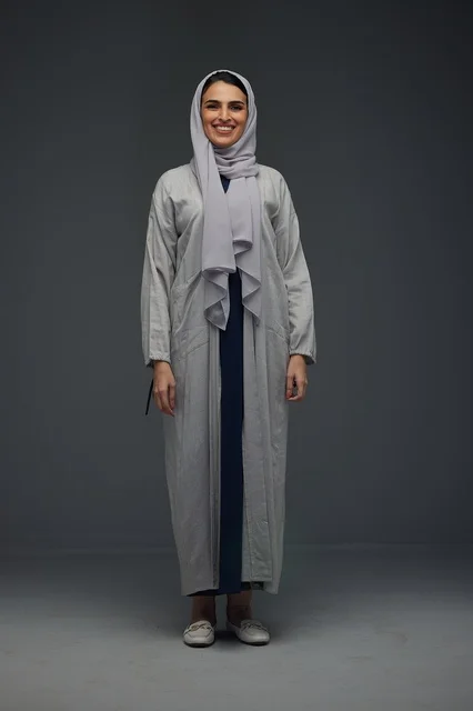 Smiling Saudi Woman in Grey Abaya on Studio Background
