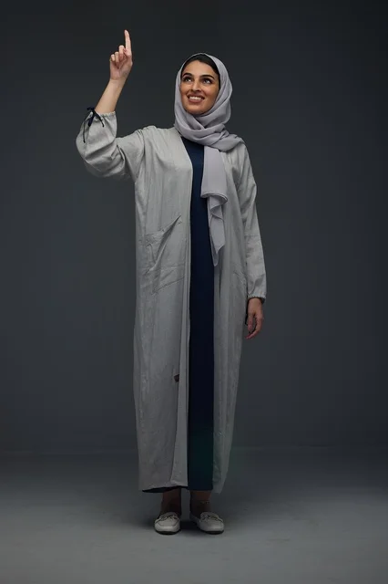 Smiling Saudi Woman in Grey Abaya Pointing Upward