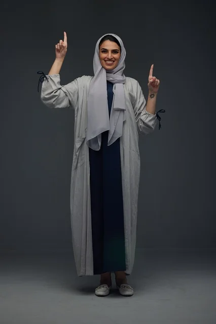 Smiling Saudi Woman in Grey Abaya Pointing Upwards