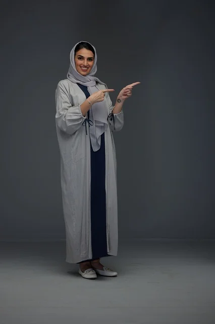 Saudi Woman Pointing in Gray Abaya on Studio Background