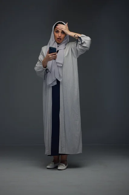 Shocked Saudi Woman with Smartphone in Grey Studio