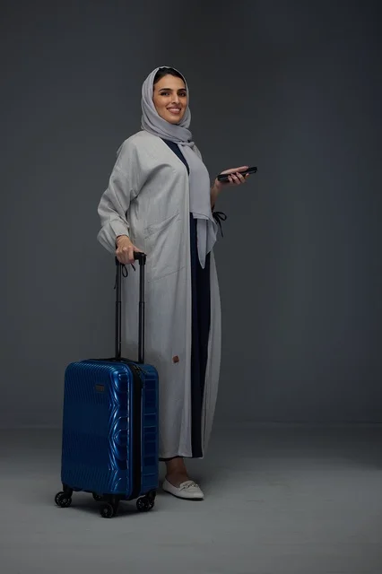 امرأة سعودية مسافرة مع حقيبة سفر وهاتف ذكي