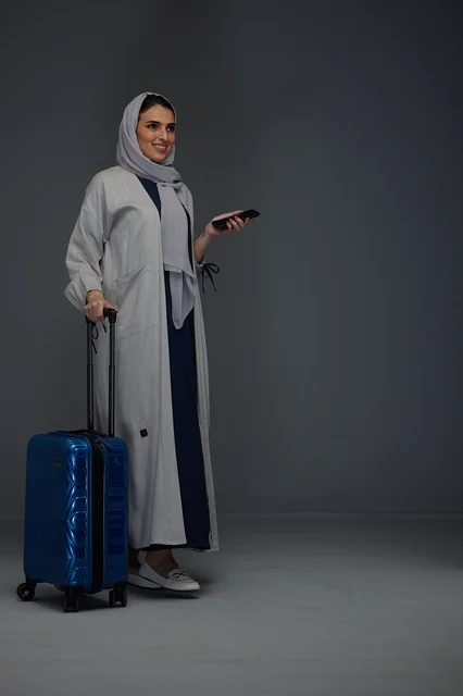 امرأة سعودية مسافرة مع حقيبة سفر وهاتف ذكي