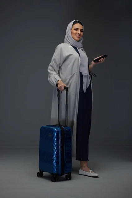 امرأة سعودية مسافرة مع حقيبة زرقاء وهاتف ذكي