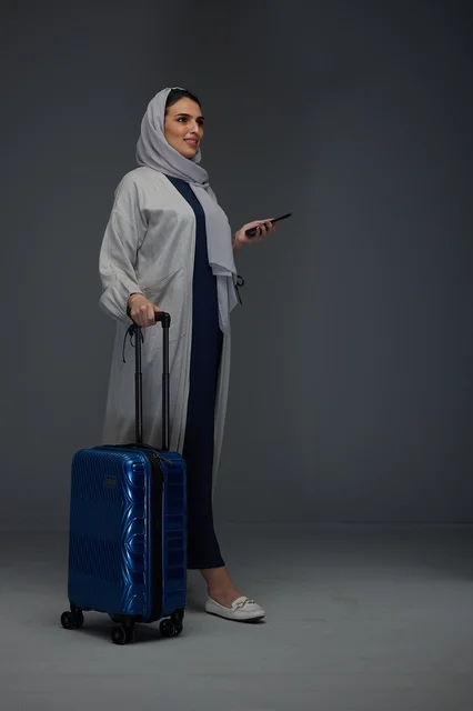 امرأة سعودية مسافرة مع حقيبة سفر وهاتف ذكي