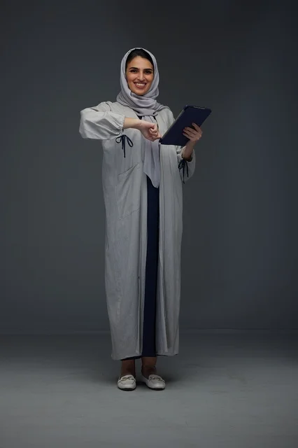 امرأة سعودية مبتسمة تستخدم جهاز لوحي في الاستوديو
