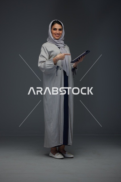 امرأة سعودية مبتسمة تستخدم جهازا لوحيا في استوديو