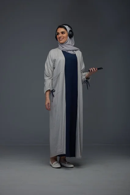 امرأة سعودية بسماعات رأس في استوديو رمادي