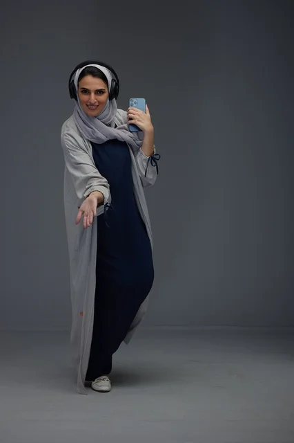 امرأة سعودية مع سماعات رأس وهاتف ذكي في الاستوديو