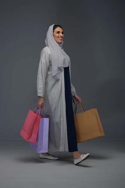 امرأة سعودية تحمل أكياس تسوق ملونة في استوديو تصوير
