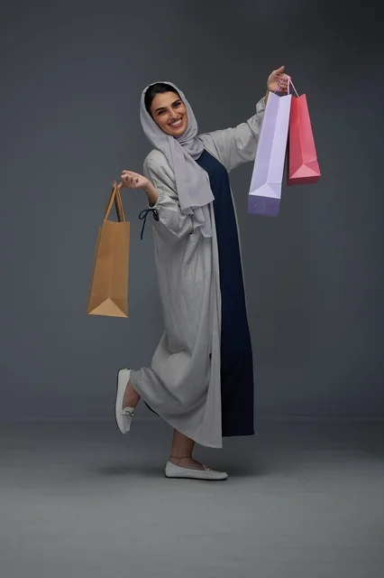 امرأة سعودية مبتسمة تحمل أكياس تسوق ملونة