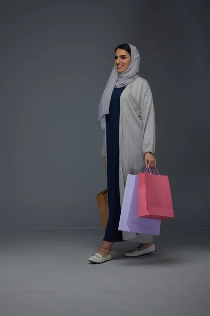 امرأة سعودية تمشي وهي تحمل أكياس تسوق ملونة