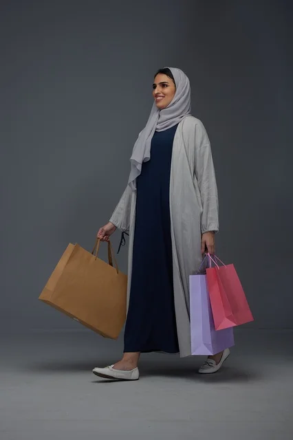 امرأة سعودية مبتسمة تحمل أكياس تسوق في الاستوديو