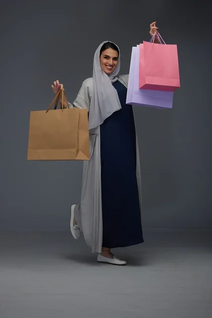 Smiling Saudi Woman Holding Colorful Shopping Bags in Studio