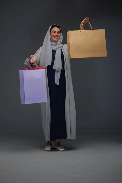 امرأة سعودية تحمل أكياس تسوق بابتسامة في الاستوديو