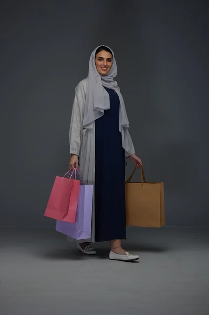 امرأة سعودية بابتسامة تحمل أكياس تسوق في الاستوديو