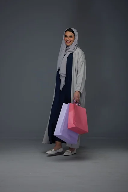 Smiling Saudi Woman Holding Shopping Bags in Studio