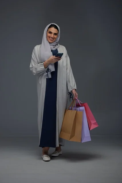 Saudi Woman with Shopping Bags and Smartphone in Studio