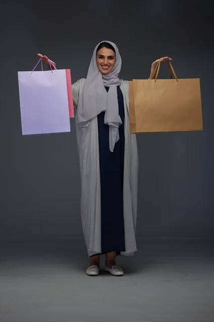 امرأة سعودية تحمل أكياس تسوق بخلفية رمادية