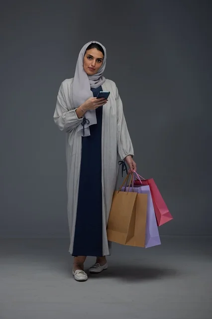 Saudi Woman with Shopping Bags and Smartphone in Studio