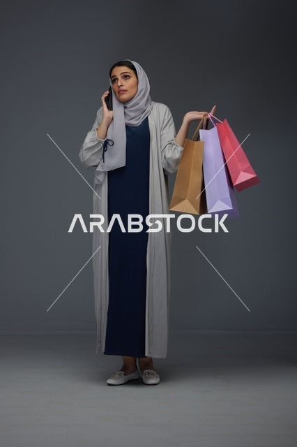امرأة سعودية تتسوق وتتحدث عبر الهاتف الذكي