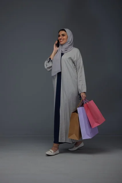 امرأة سعودية تحمل حقائب تسوق وتتحدث بالهاتف امرأة سعودية تحمل حقائب تسوق وتتحدث بالهاتف