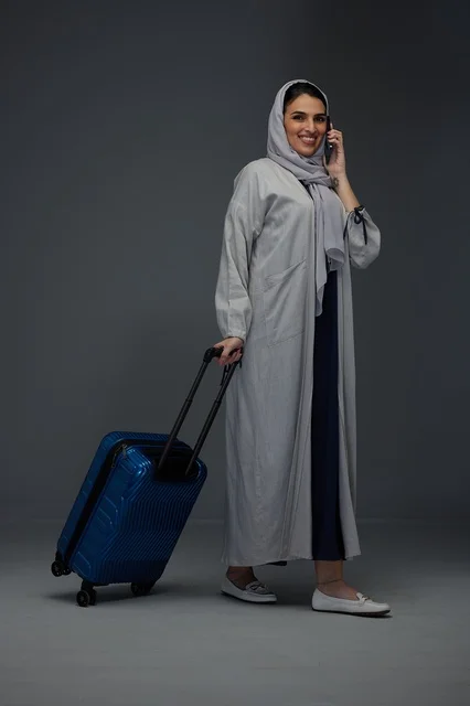 Saudi Woman with Blue Suitcase Talking on Mobile Phone