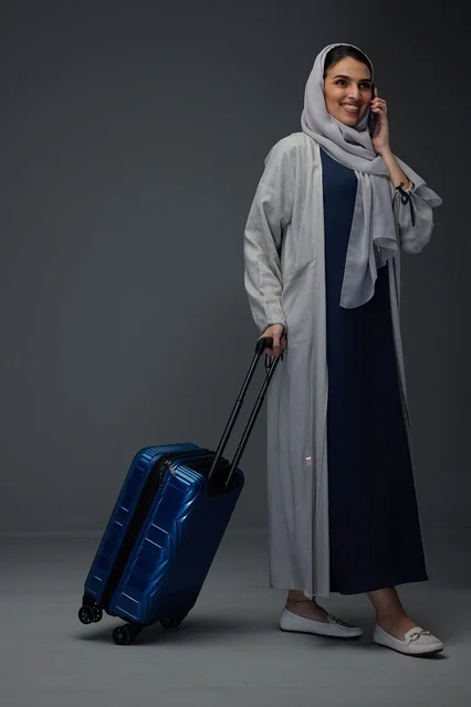 Saudi Woman with Suitcase Talking on Smartphone in Studio