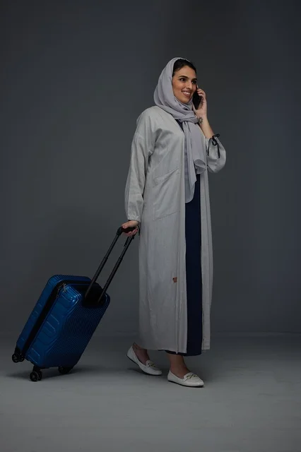 امرأة سعودية تسافر بحقيبة سفر تتحدث عبر الهاتف