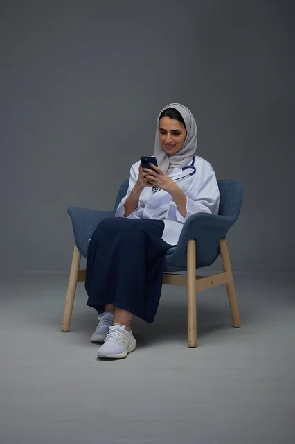 Saudi Female Doctor Using Smartphone in Armchair