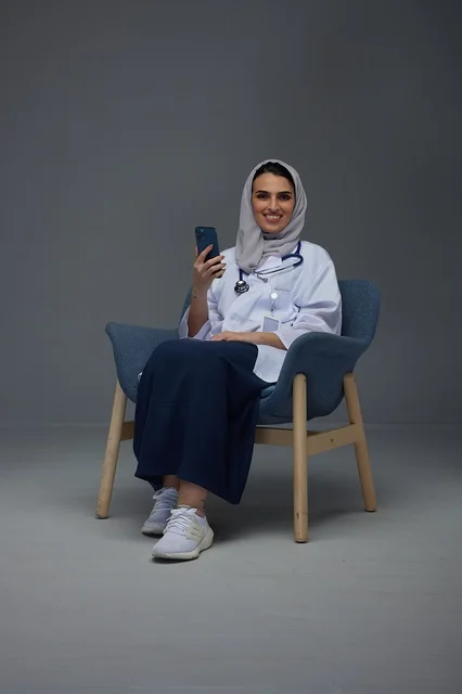 Saudi Female Doctor Sitting with Smartphone in Studio