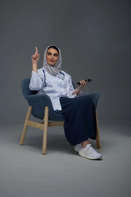 Saudi Female Doctor Pointing Up in Grey Studio Setting