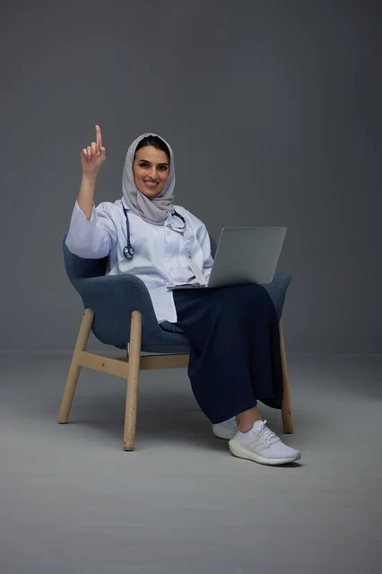 Saudi Female Doctor with Laptop Gesturing Upward